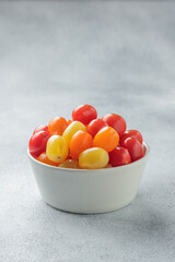 Yellow, orange and red cherry tomatoes in a white bowl