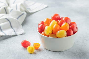 Yellow, orange and red cherry tomatoes in a white bowl