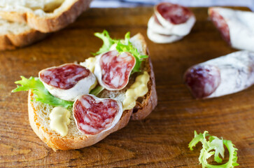 Sandwich with Catalan thin sausage with mold - fuet, on a wooden cutting board. Horizontal orientation.