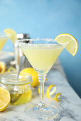 Delicious bee's knees cocktail and ingredients on white marble table against light blue background