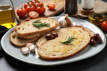 Tasty bruschettas with oil and rosemary on plate, closeup