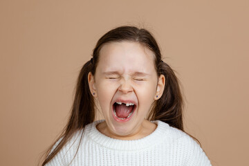 Portrait of young furious angry girl with long dark hair in pink, white sweater standing with...