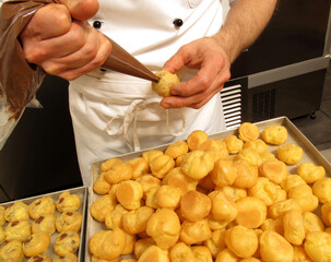 pastry cook injecting chocolate cream on sweets cupcakes