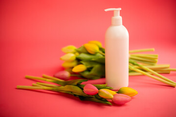 Mockup of beauty cosmetic makeup bottle product with skincare healthcare concept on pink background with tulips.