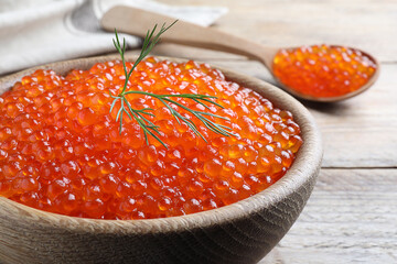 Bowl with delicious red caviar and dill on wooden table, closeup