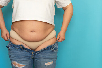 Cropped photo of fat plump plus-size overweight woman wearing white short T-shirt, standing on blue...