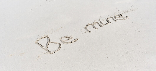 Text Be mine written on white sand of tropical beach.