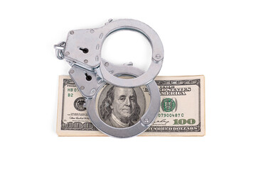 handcuffs lying on a wad of dollars. Benjamin Franklin in the ring. isolated on a white background