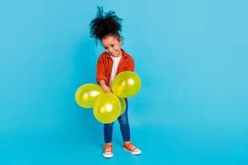 Fototapeta na wymiar Full size photo of sweet wavy small girl with balloons wear shirt jeans footwear isolated on blue background