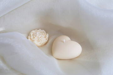 Handmade candle heart and flower on the gentle textile background. Natural eco-friendly home decor. Spa composition.