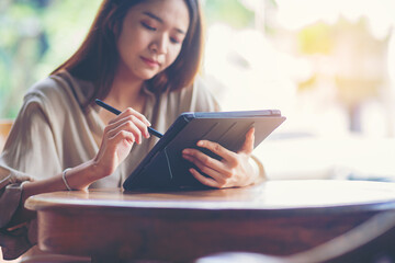 Obraz premium Woman using digital tablet computer at workplace. Businesswoman hand holding pen and touching screen of tablet device.