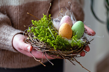 woman hands holding painted easter eggs in a small bird nest - Powered by Adobe