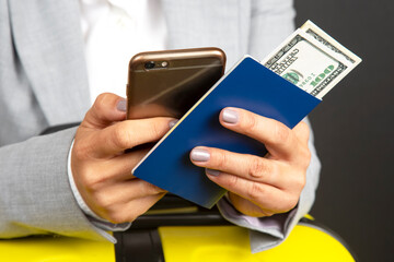 hands with a phone, passport and money against the background of a luggage bag. travel and leisure
