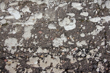 Fragment of an old road with cracked asphalt, stones and moss. Background image.