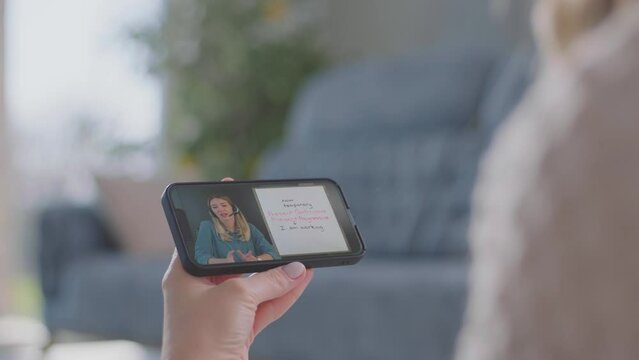 Teen Woman college student holding mobile and having online class with math teacher tutor using mobile zoom app video conference 