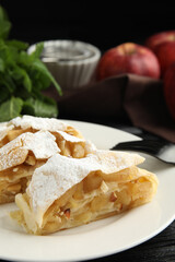 Delicious apple strudel with almonds and powdered sugar on plate, closeup. Space for text