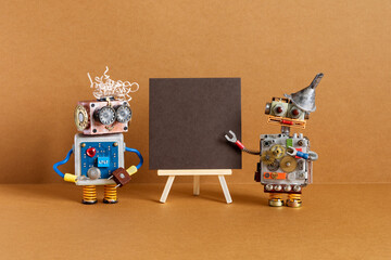 Two robots and brown paper placard set on wooden easel. copy space for text.