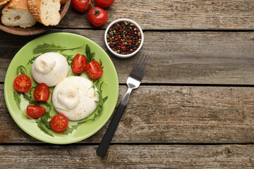 Delicious burrata cheese with arugula and tomatoes on wooden table, flat lay. Space for text