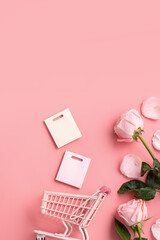 Mother's Day shopping design concept background with pink rose flower and cart on pink background.