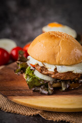 Burger served with french fries on a wooden plate.