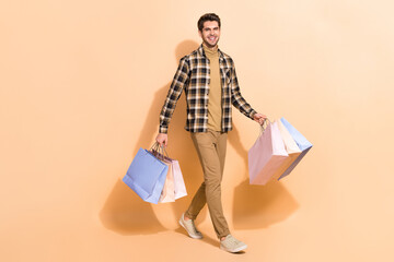 Full length body size view of attractive guy visiting store wearing checked shirt carrying bags...
