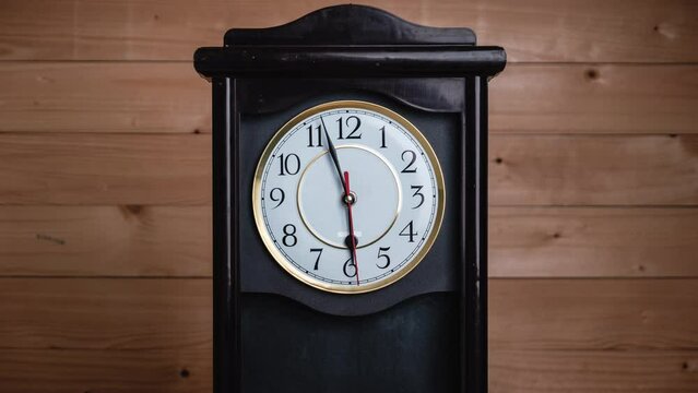 Timelapse of vintage clock with full turn of time hands at 6 pm or am on wooden background. Old Retro wall clock with white circular dial. Old-fashioned antique clock. Arrows second, minute, and hour