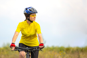 beautiful and happy woman cyclist rides a bicycle on the road in nature. Healthy lifestyle and sports. Leisure and hobbies