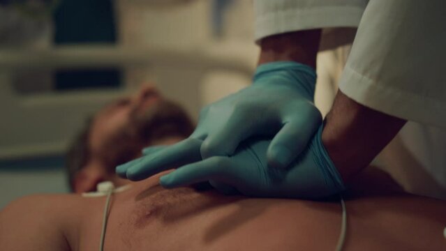 Closeup doctor doing heart massage to unconscious patient in hospital ward.