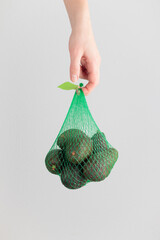 Hand holding an avocado bag on a white background