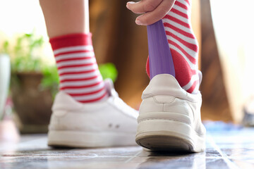 Person puts a shoehorn into sneakers closeup