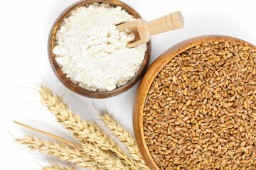 Ripe wheat ears, wheat grain and flour in a wooden bowl on white background. Top view