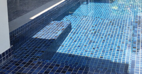 clear water in the swimming pool is covered with mosaics