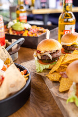 mini burgers as sliders served with nachos on a table full of food
