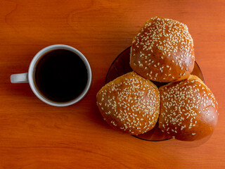 A cup of coffee and three buns on the table top view. White ceramic coffee cup. Breakfast. Coffee.
