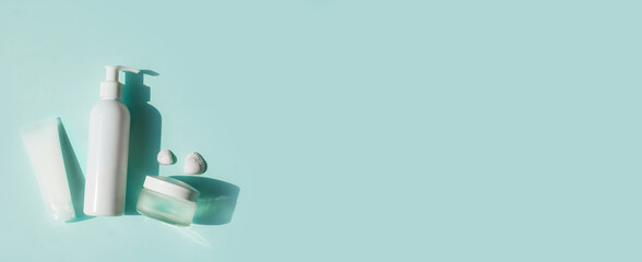 Eco-friendly cosmetics for face and body skin care. White tube, bottle and jar of cream on a blue background. Hard Shadows.