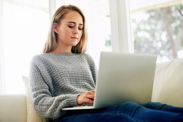 Naklejka premium Blogging his her new favourite hobby. Cropped shot of an attractive young woman using her laptop while chilling at home.