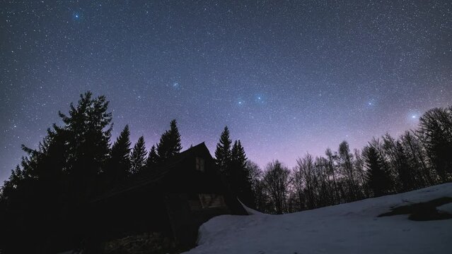 Astronomy time lapse Starry night sky and stars above wooden hut in wilderness forest nature