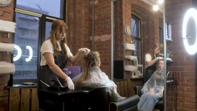 Beauty salon. fashion stylist takes care of client. master prepares hair for painting. professional stylist works with beautiful girl to create an image of lady