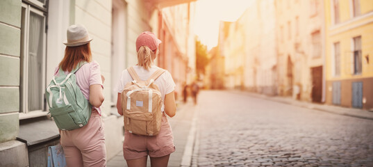 Two woman with backpacks walking in the old Tallinn, Estonia.