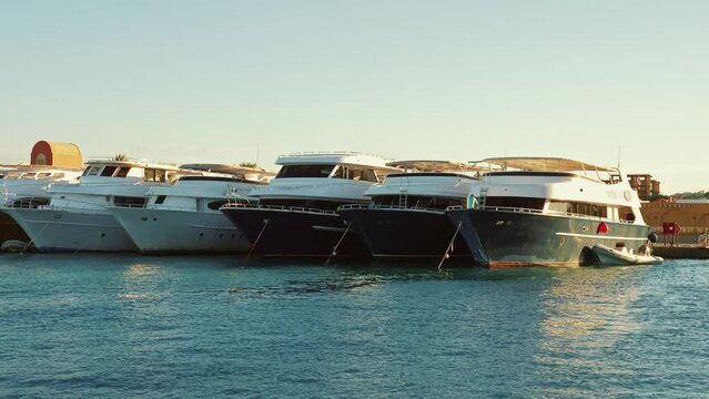 Yachts, boats are at city pier. Ships floating in sea harbor. Marine landscape with holiday cruisers, motorboats, water crafts. Sunny day. Yachting, sailing, travelling, seaport