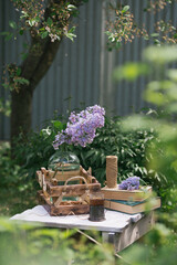 A beautiful postcard. Old books, a wooden box, a bouquet of purple lilacs in the garden. Still-life. Spring. The concept of "Good morning". Processing in the style of an old film.