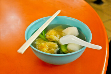 Famous Singaporean dumpling soup in a food court hawker center served in blue bowl