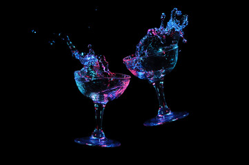Set glass with alcohol splash levitating in bright blue and deep red concept, black background