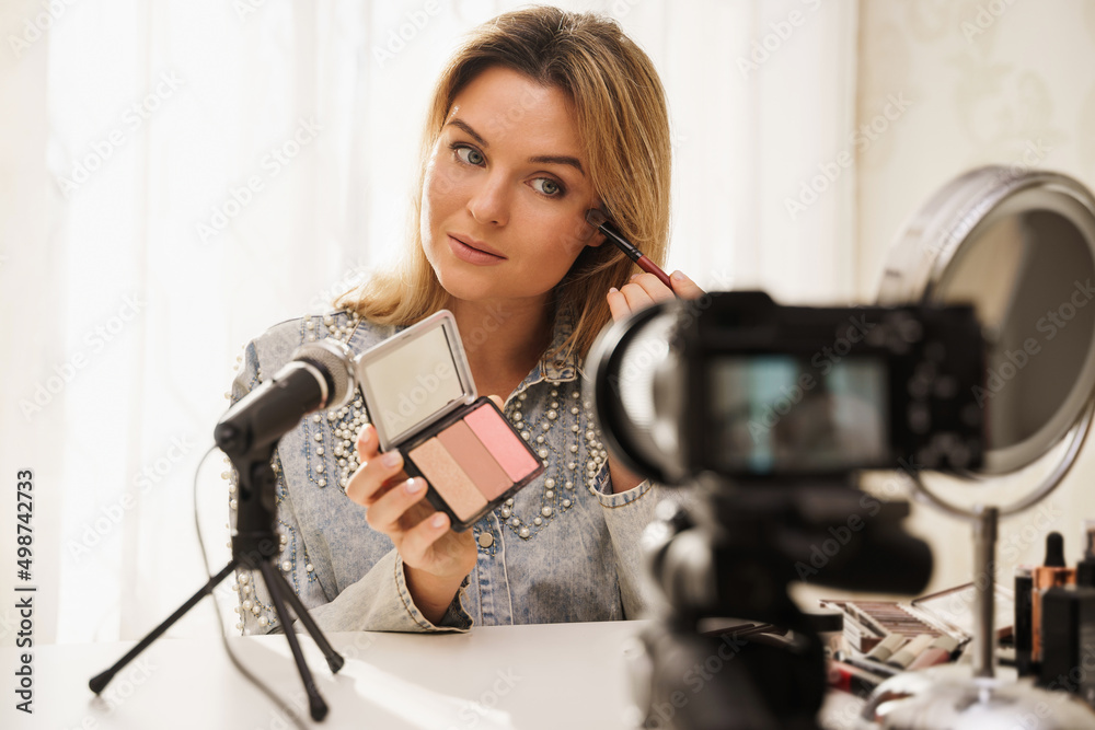 Canvas Prints beauty blogger applying blush on her face during video tutorial recording for her followers