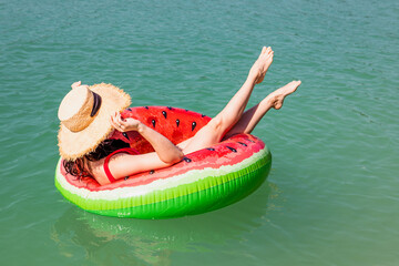 beautiful woman floating on inflatable ring in blue lake water