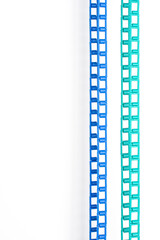 Obraz premium Blue and green plastic chains are hanging on a white wall. Vertical picture.