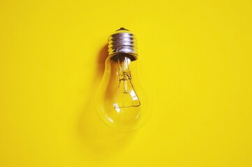 Electric power concept flat lay photography. Save electricity concept. Energy crisis. Light bulb on a bright yellow background top view image