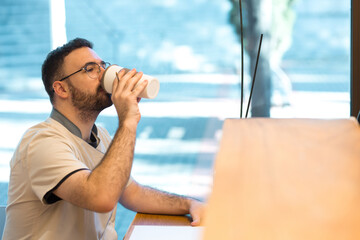 Receptionist taking drink of coffee from his reusable cup