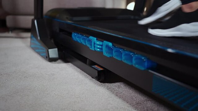 female feet running on treadmill damping in sport shoes, close up
