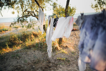 Linen clothes are dried on a rope among trees, sand and beach and clothesline